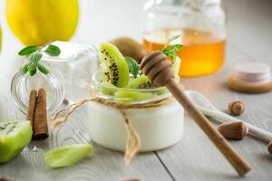 Homemade yogurt in a glass jar with honey, kiwi, nuts. photo