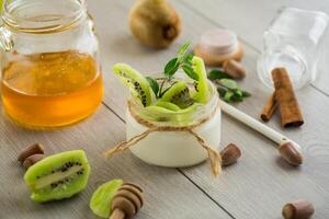 Homemade yogurt in a glass jar with honey, kiwi, nuts. photo