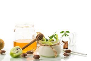 Homemade yogurt in a glass jar with honey, kiwi, nuts. Isolated on white background photo