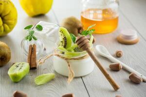 Homemade yogurt in a glass jar with honey, kiwi, nuts. on wooden table photo