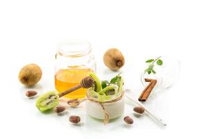 Homemade yogurt in a glass jar with honey, kiwi, nuts. Isolated on white photo