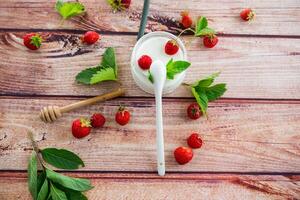 homemade sweet yogurt in a jar with strawberries, on a wooden table photo