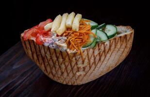 Doner with a crispy crust and delicious meat and vegetable filling on a dark background. photo