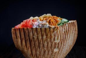 Doner with a crispy crust and delicious meat and vegetable filling on a dark background. photo