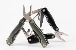 Steel multitool isolated on white background. Opened multitool with pliers, file, blade, screwdriver, bottle opener and saw, with a white background. Multi tool with expanded tools and pliers photo