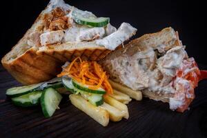 Cut doner with a crispy crust and delicious meat and vegetable filling on a dark background. photo