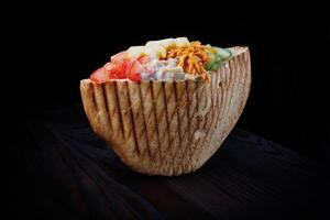 Doner with a crispy crust and delicious meat and vegetable filling on a dark background. photo