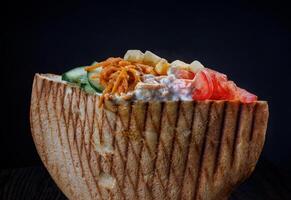 Doner with a crispy crust and delicious meat and vegetable filling on a dark background. photo