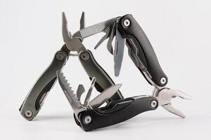 Steel multitool isolated on white background. Opened multitool with pliers, file, blade, screwdriver, bottle opener and saw, with a white background. Multi tool with expanded tools and pliers photo