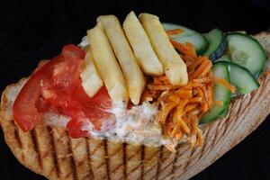 Doner with a crispy crust and delicious meat and vegetable filling on a dark background. photo