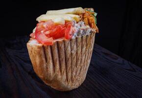 Doner with a crispy crust and delicious meat and vegetable filling on a dark background. photo