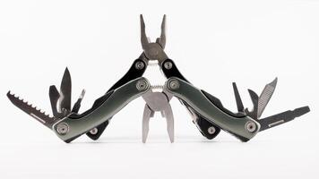 Steel multitool isolated on white background. Opened multitool with pliers, file, blade, screwdriver, bottle opener and saw, with a white background. Multi tool with expanded tools and pliers photo