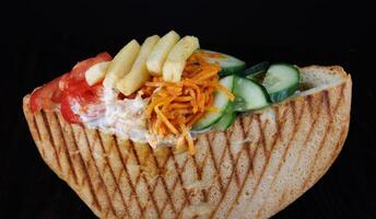 Doner with a crispy crust and delicious meat and vegetable filling on a dark background. photo
