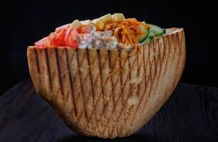 Doner with a crispy crust and delicious meat and vegetable filling on a dark background. photo