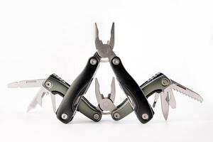 Steel multitool isolated on white background. Opened multitool with pliers, file, blade, screwdriver, bottle opener and saw, with a white background. Multi tool with expanded tools and pliers photo