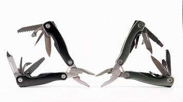 Steel multitool isolated on white background. Opened multitool with pliers, file, blade, screwdriver, bottle opener and saw, with a white background. Multi tool with expanded tools and pliers photo