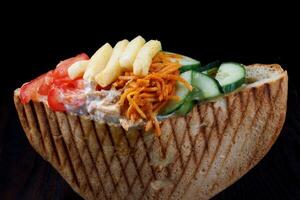 Doner with a crispy crust and delicious meat and vegetable filling on a dark background. photo