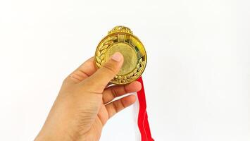 The winner's gold medal is held in the athlete's raised hand on a white background photo
