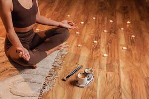 Yoga meditation at home. Relaxation concept with calm young healthy woman sitting in front of candles and aroma sticks photo