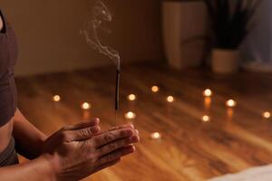 Meditative moment with incense and candles, smoking aroma stick close up. aromatherapy photo