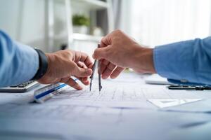 Two men are holding a pair of compasses and drawing on a piece of paper. Concept of collaboration and teamwork, as the two men work together to create something photo