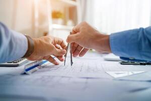 Two people are holding a pair of compasses and looking at a piece of paper. Scene is focused and serious, as the two people are likely working on a project or task that requires precise measurements photo