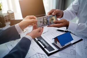 A man is handing a key to another man. The man holding the key is wearing a suit and tie. The other man is wearing a white shirt. Concept of professionalism and trust between the two men photo