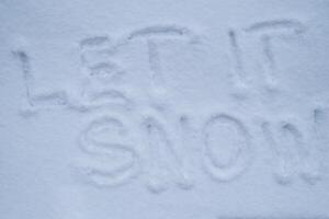 LET IT SNOW text handwritten in snowy winter season surface. Freezing cold weather. Climate change challenging conditions concept photo