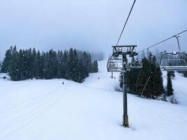 esquí levantar Nevado montaña invierno bosque con silla levantar a el esquí recurso en invierno. Nevado clima esquí Días festivos invierno deporte y al aire libre ocupaciones al aire libre turismo esquiar Snowboarding foto
