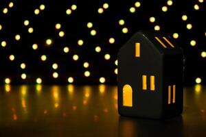 Christmas clay lantern house on dark bokeh light garland background. New year and Christmas preparation. Handmade eco-friendly decor. Sustainable Christmas decoration. Copy space photo