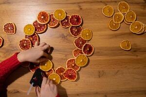 Step 2 Step by step instruction of making handmade Christmas wreath made of dry fruits oranges and grapefruits. Female hands creating craft homemade decor. New year celebration. Winter holidays photo