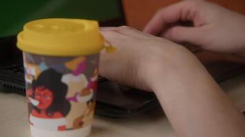 Close up of hands working at the laptop of the computer. Stock footage. Typing on keyboard with a cup of coffee standing near. video