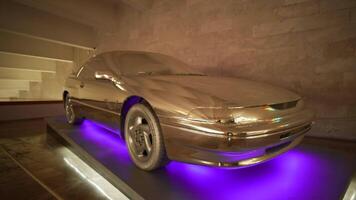 Illuminated car in showroom. Action. Cool car with gilding and backlit bottom. Neon illumination from bottom of car and gold painting. Auto Dealership video