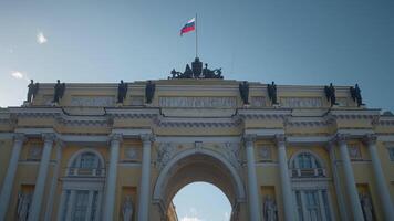Bottom view of arch of ancient architectural building. Action. Beautiful arch of ancient building with waving flag on background blue sky background. Beautiful old architecture with arch on sunny day video
