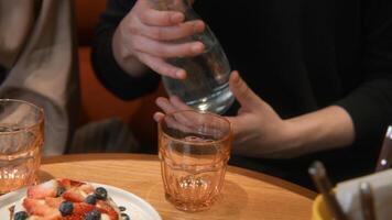 Close-up of guy pouring water in cafe. Stock footage. Guy on date pours water from jug into glasses.. Drinking water in jug with glasses in cafe video