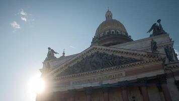 View from below of ancient cathedral with statues and dome. Action. Beautiful old cathedral on background of bright sun and blue sky. Dome and statues in architecture of ancient cathedral video