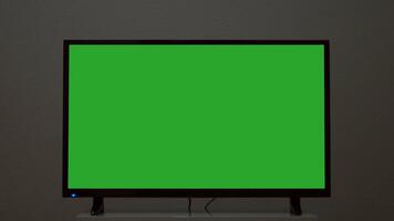 Plasma TV with green screen stands on background wall. Concept. Green-screen TV stands on background gray wall. Green screen TV for inserting chromakey video