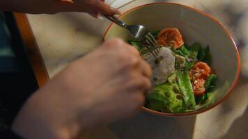 Close-up of woman cutting poached egg in salad. Stock footage. Delicious restaurant salad with poached egg. Instagram breakfast or lunch with liquid poached egg on green juicy salad video