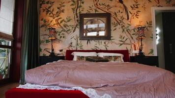 Bed in bedroom with walls with nature ornament. Creative. Decorative walls with tree branches and birds. video
