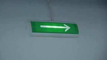 Glowing green arrow on wall. Clip. Arrow on green background lights up to indicate exit. Arrow of evacuation exit glows with green background on wall in building video