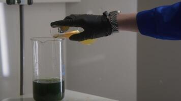 Close up of man pouring mixture in a beaker with solution inside. Stock footage. Equipment at the laboratory. video