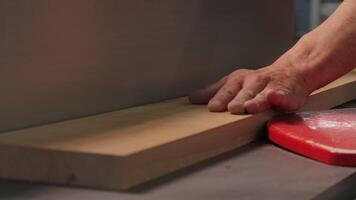Close-up of worker cutting wooden board with machine. Creative. Homemade machine for discharging wooden boards in workshop. Man cuts wooden board with machine tool in creative workshop video