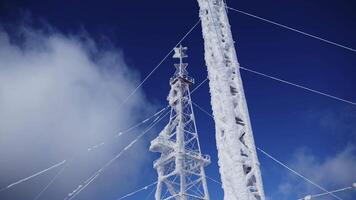 High voltage wires and poles are covered with frost on a blue cloudy winter sky. Clip. Low angle view of frozen power lines. video