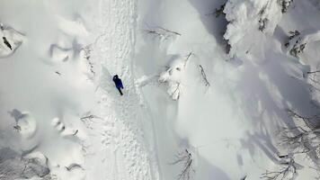 Top view of man walking into mountains in winter forest. Clip. Man goes on winter hike in mountains. Man walks alone uphill in winter in forest video