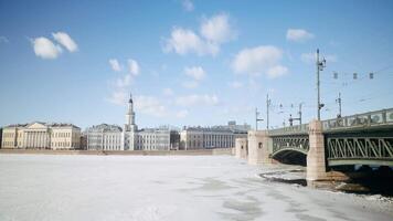 Beautiful view of ancient city with bridge and frozen river. Action. Ancient city with 18th century architecture on sunny winter day. Ancient city with frozen river on sunny day video