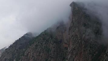 Clouds passing over mountain peak forming different shapes video
