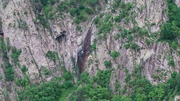 Waterfall cascading down rocky mountain cliff video