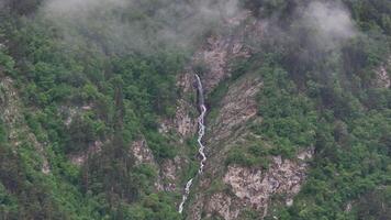 Fog slowly revealing a waterfall flowing down a mountain video