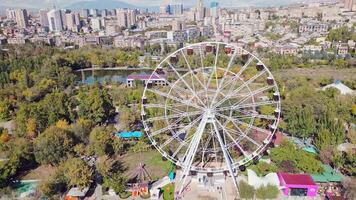Yerevan, Armenia - 19th october, 2024- Aerial fast motion zoom out view ferris wheel in Victory Park ir with cityscape and buildings of Yerevan. Sunny autumn day carousels day out things to do concept video