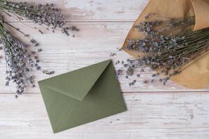 Empty green envelope paper template mock up. Copy space for your text. Lavender flower. Greeting or invitation card blank with envelope. Top view, flat lay photo